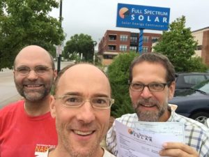 Photo of Brian Lavendel with friends in front of Full Spectrum Solar sign.